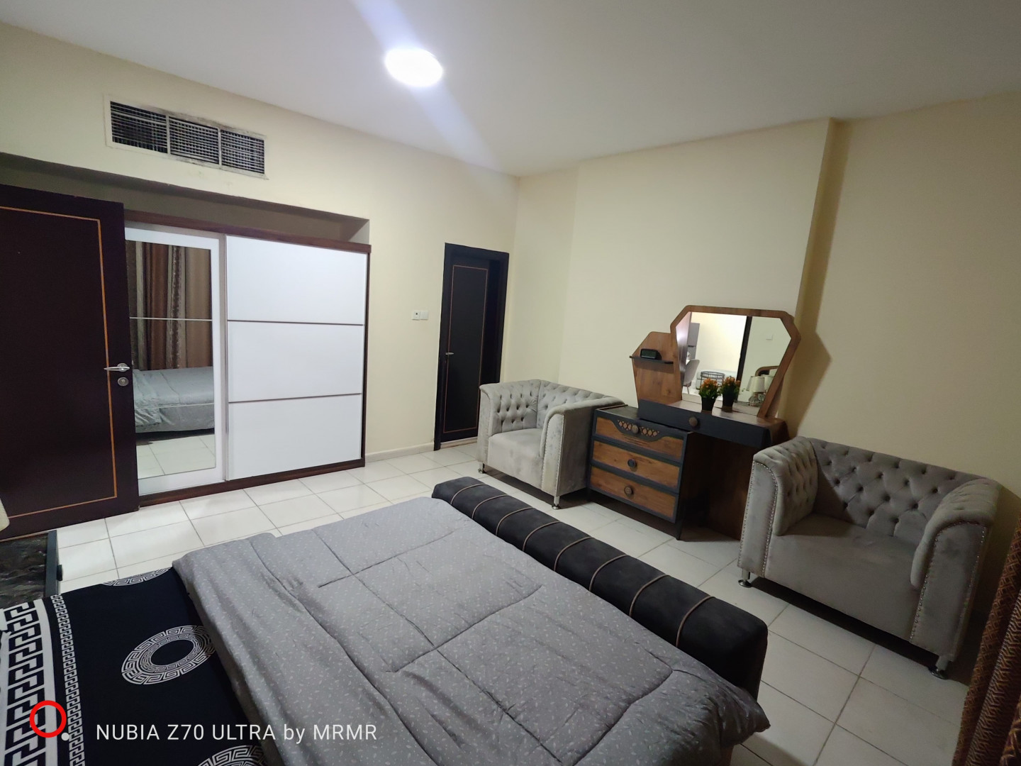One bedroom and living room furnished with hotel furniture
